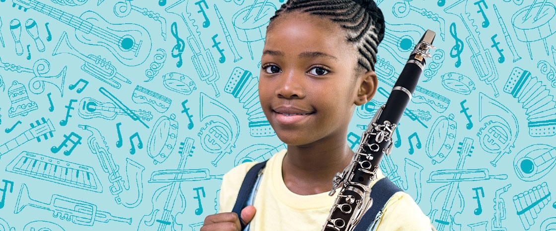 A girl smiling while carrying a flute with a bunch of other instruments in background